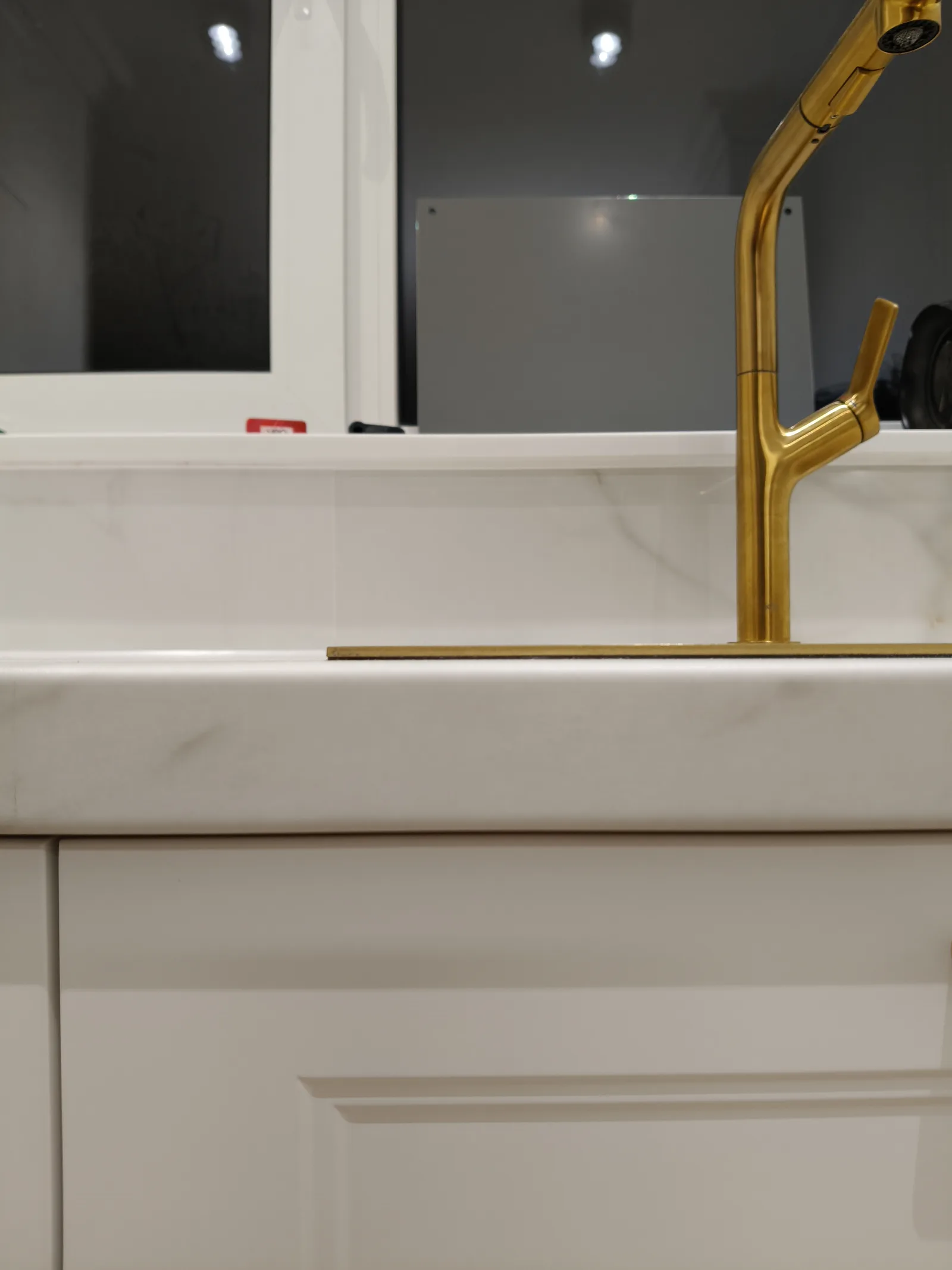 Kuchnia na wymiar, zbliżenie na złotą baterię i zlew