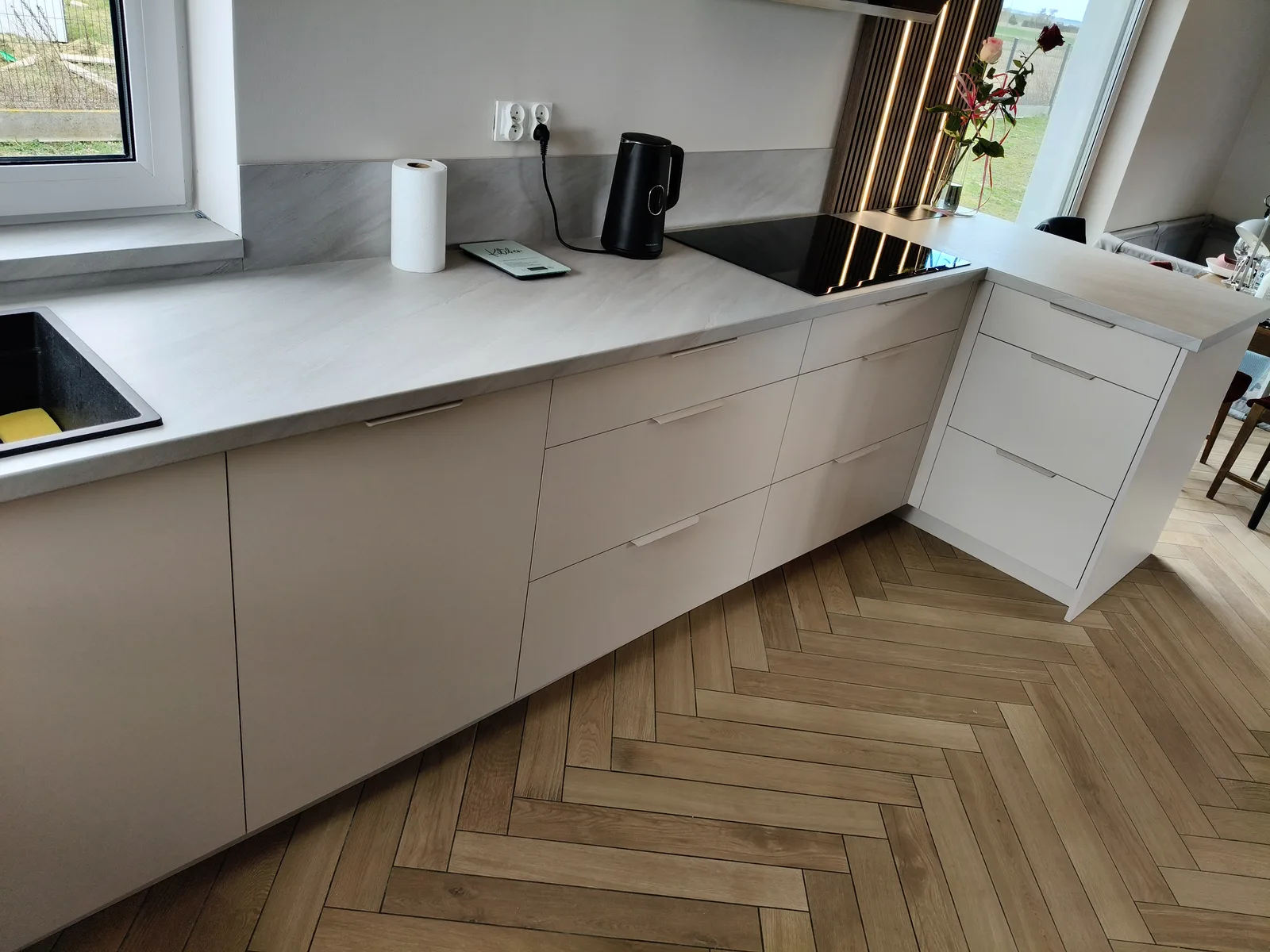 Kuchnia na wymiar w bieli, podłoga w jodełkę i okno
