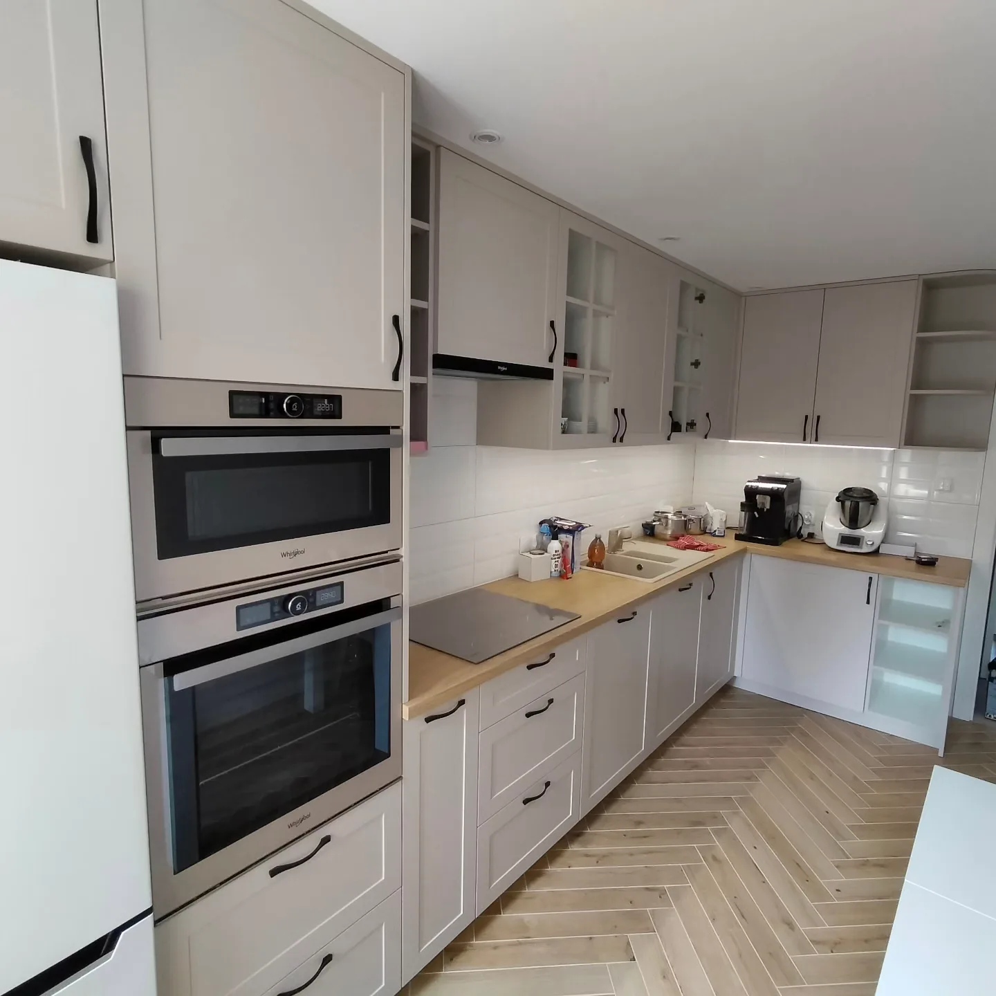 Kuchnia na wymiar w bieli, podłoga w jodełkę i podwójny piekarnik