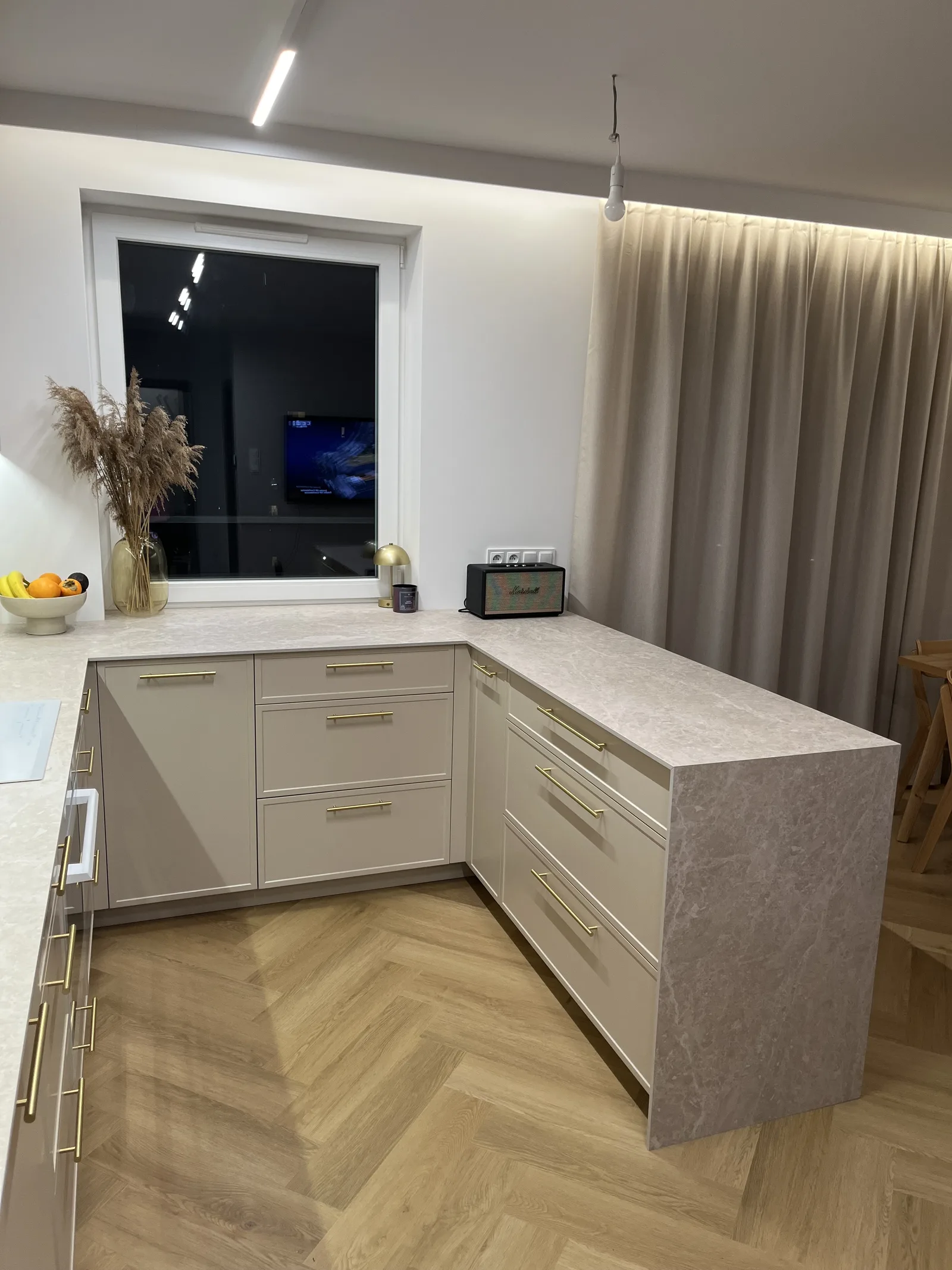 Kuchnia na wymiar w taupe, widok wieczorny przy oknie