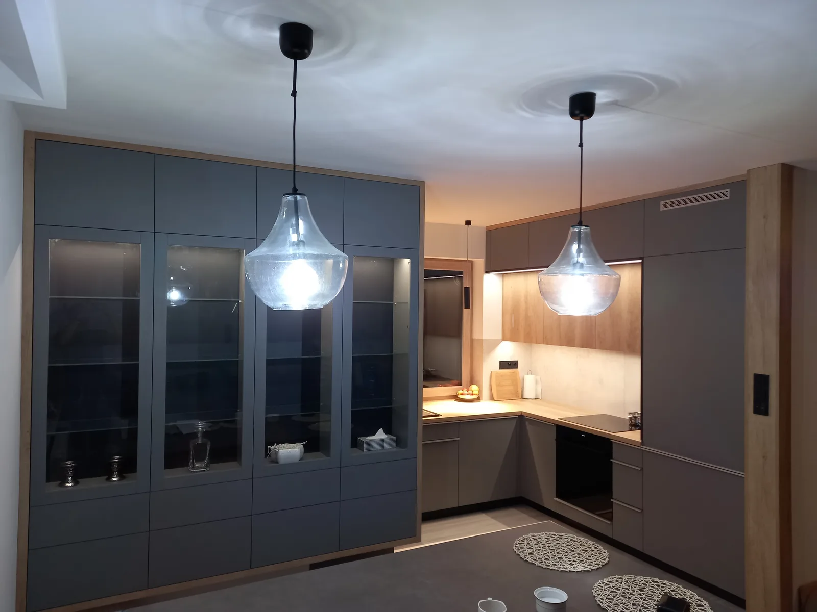 Kuchnia na wymiar z jadalnią, witryny i lampy wiszące nad stołem